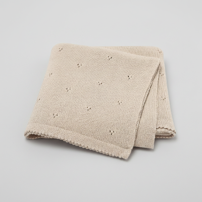 Couverture bebe tricot beige plier sur fond gris pale