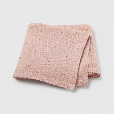 Couverture bebe tricot rose poudrée plier sur fond gris pale
