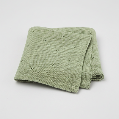 Couverture bebe tricot verte plier sur fond gris
