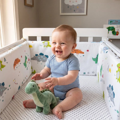 Tour de lit bébé dinosaures bébé assit souriant lit barreaux