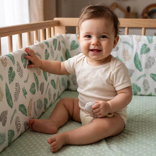 Tour de lit bébé feuilles, bébé souriant assis dans lit