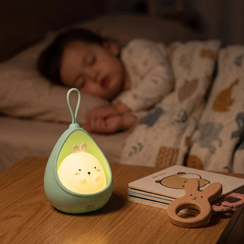 Veilleuse bébé lapin allumée près d’un nourrisson endormi