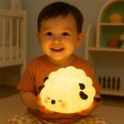 Veilleuse bébé, mouton silicone allumée tenue par un bébé souriant
