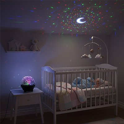 Veilleuse projection bébé sur table de chevet diffusant étoiles colorées au plafond pendant le sommeil de bébé